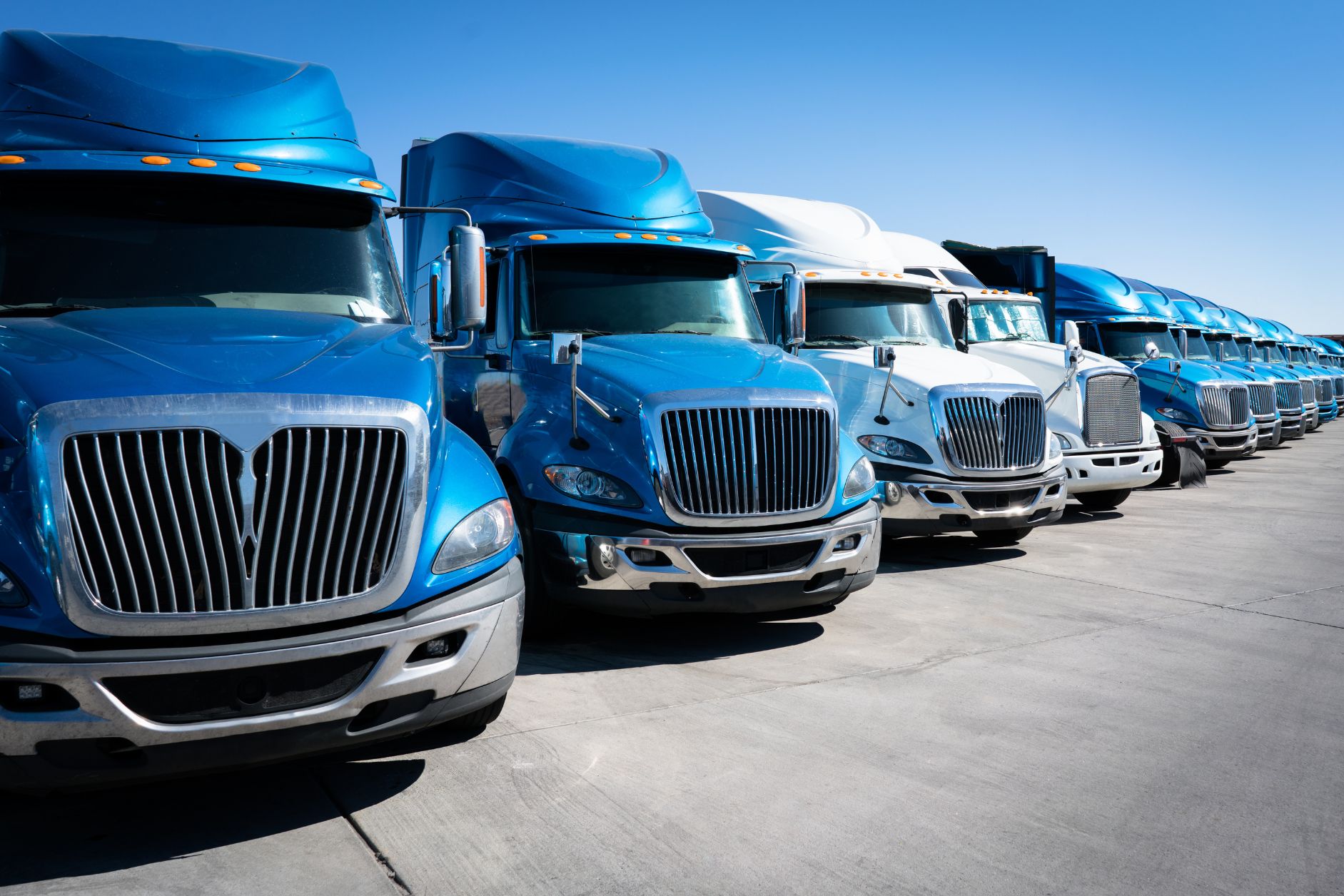 A fleet of commercial trucks lined up, representing the diverse transportation needs in the trucking industry. This image is featured in our trucking insurance blog post, illustrating the importance of comprehensive coverage for trucking businesses.